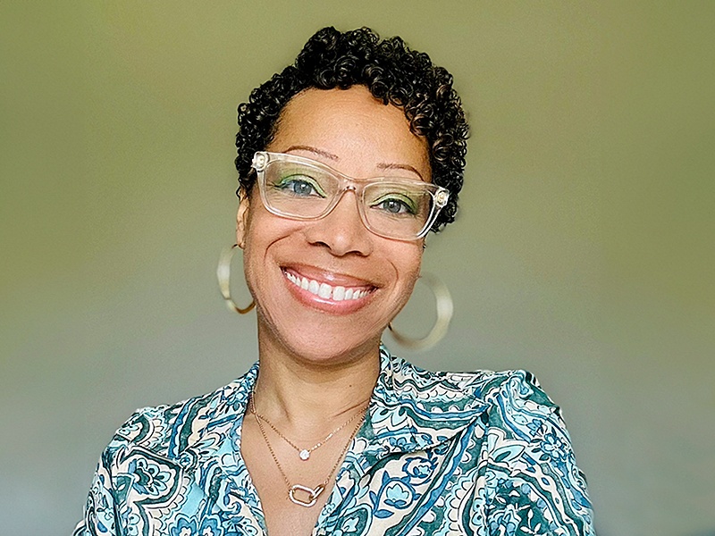 Human wearing glasses, hoop earrings, and a blue patterned shirt.