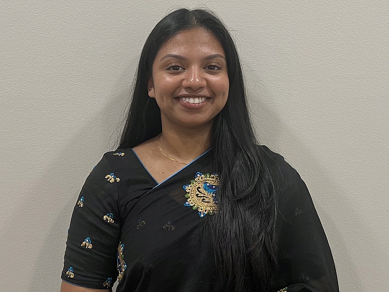 Noreen smiling and standing with a gray background
