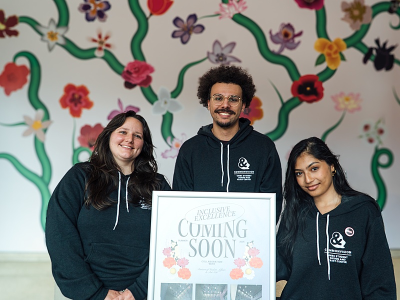 Three humans standing in front of an installation.
