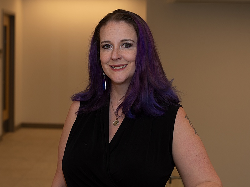 Debbie standing in the hallway with a black top smiling into the camera