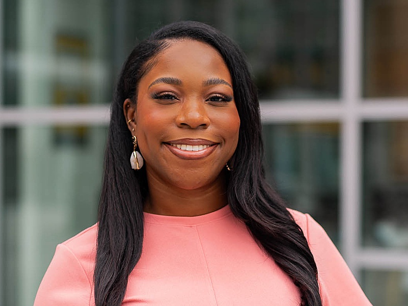 Portrait of Shakira Davidson in peach business attire on Main Street in The Commons