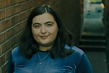 A head and shoulders shot of Johanna standing by a brick wall with steps behind her.