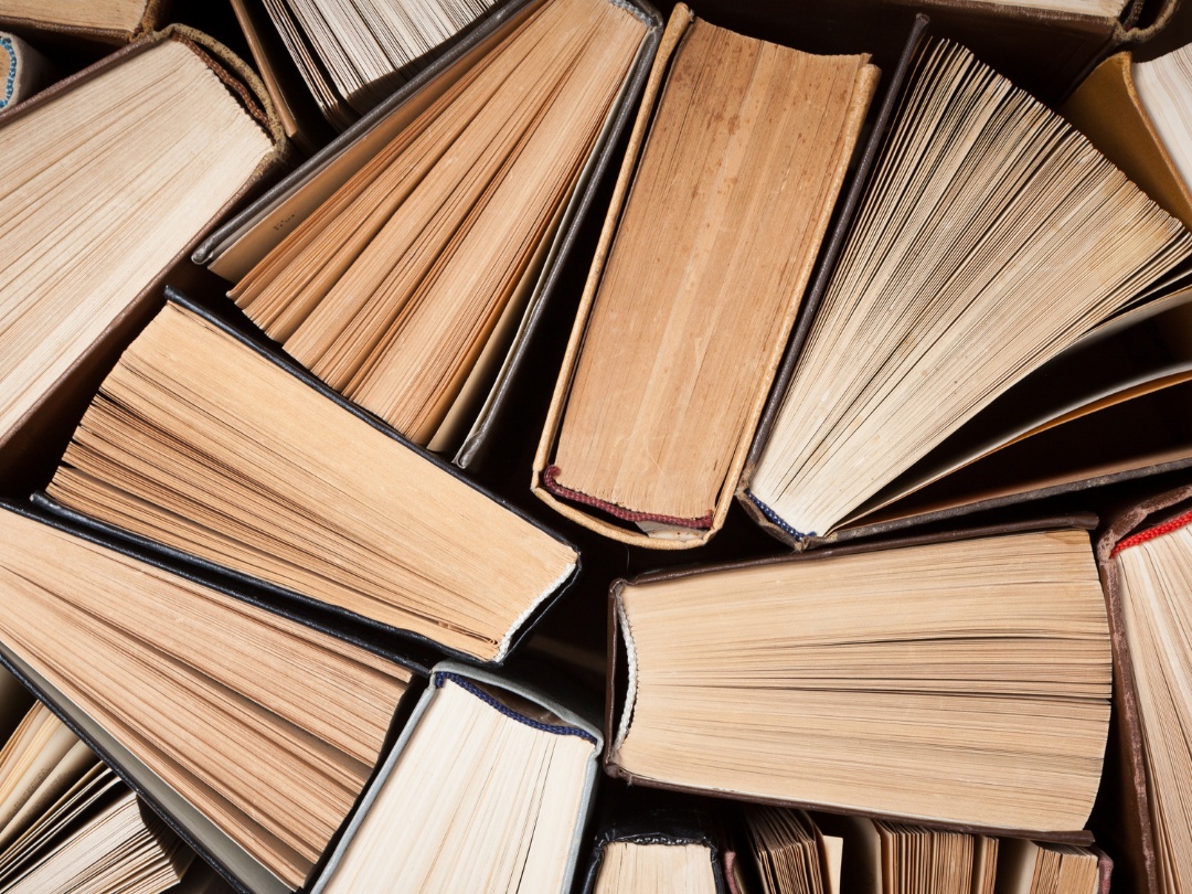 A birds eye view of multiple books, showcasing their spines and the pages. The books take up the whole screen.