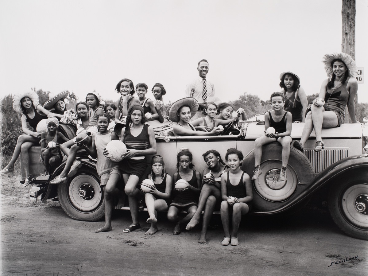 A large group of people clustered around a car. Image: Addison Scurlock, Picnic, #78, [Highland Beach, Maryland], c. 1931, printed 1982. Gelatin Silver Print, The Photography Collections, UMBC (P82-17-014).