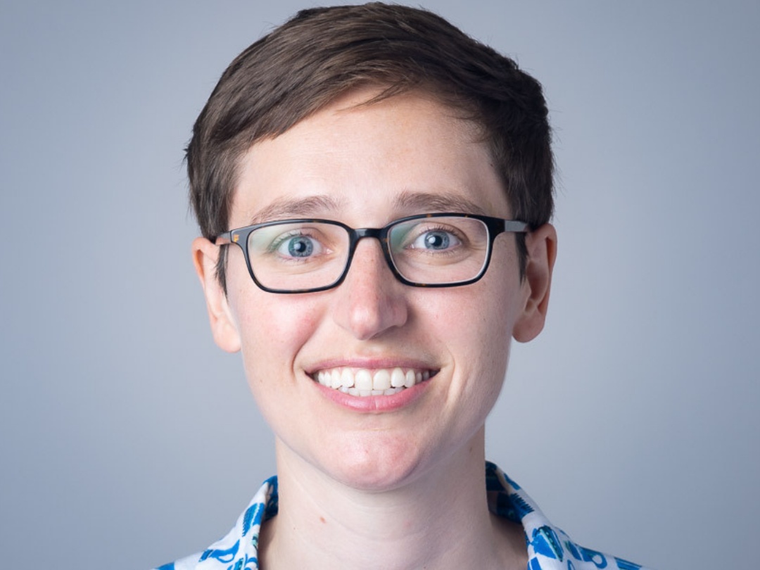 Debby Sneed is smiling towards the camera. She has short brown hair and is wearing eyeglasses.