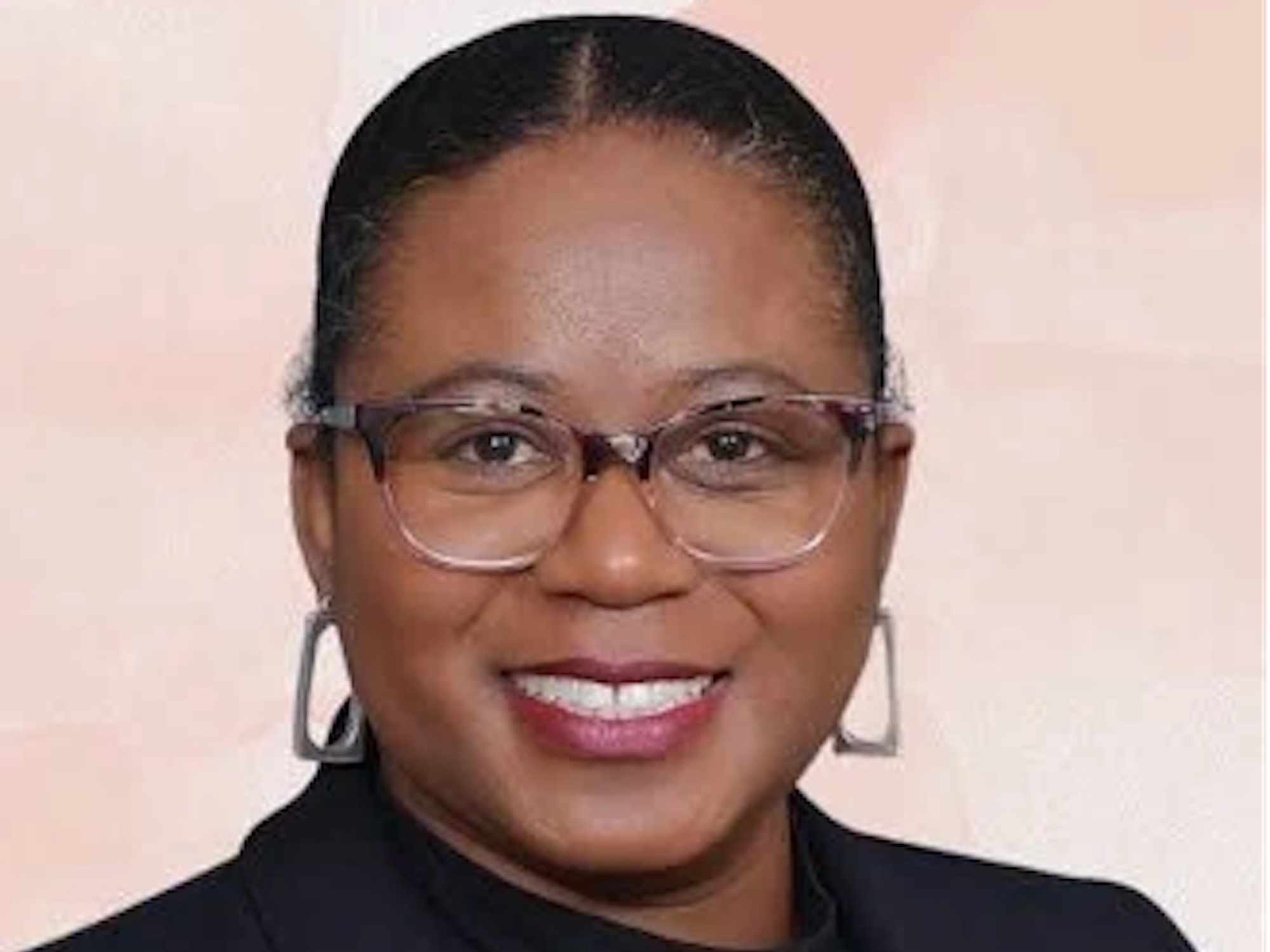 A Black woman with glasses is smiling