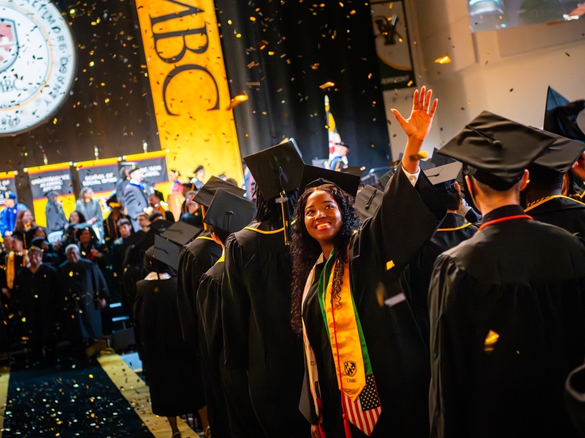 A graduate waves her hand while celebrating the Winter 2025 Undergraduate Commencement