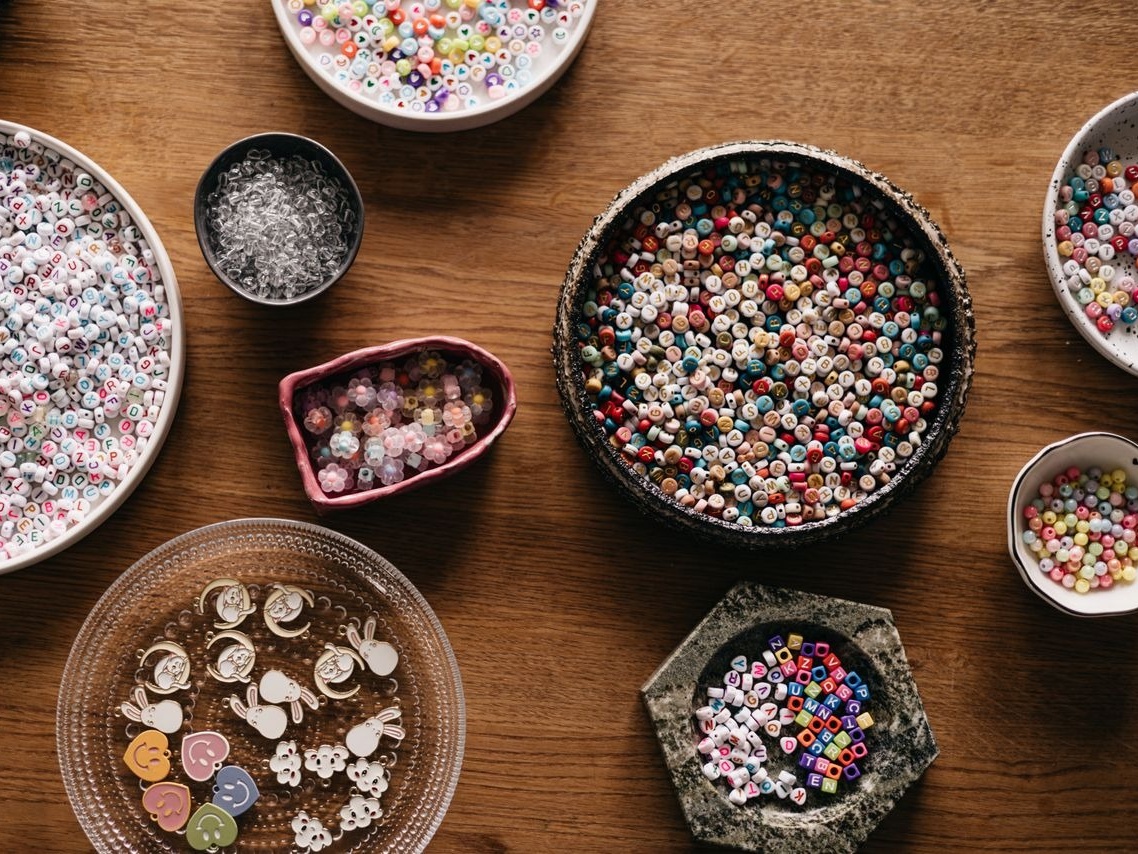 Colorful assortment of beads and charms arranged in various bowls, perfect for crafts and creativity.