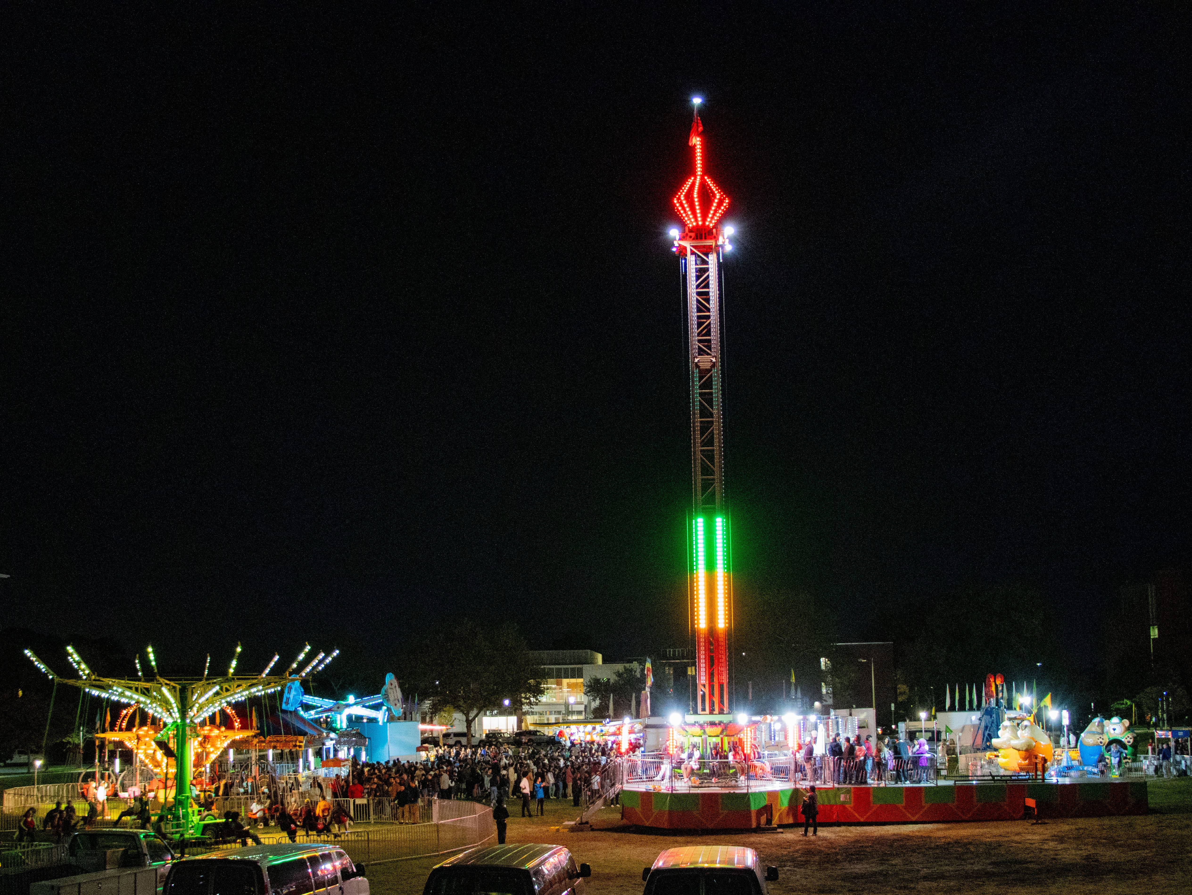 Carnival rides outside lit up at night.
